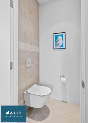 a bathroom with a toilet with a picture on the wall at Ocean House in Njarðvík