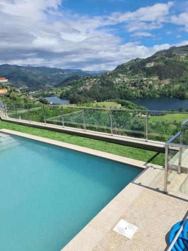 a swimming pool with a view of a river and mountains at Casa do Alto in Terras de Bouro