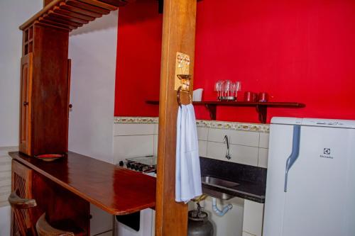 a kitchen with a refrigerator and a red wall at Pousada Flat Castor in Natal