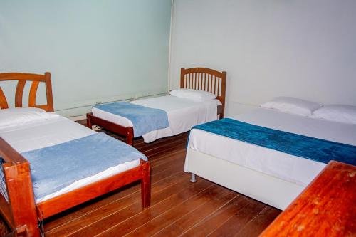 a room with three beds and a wooden floor at Pousada Flat Castor in Natal