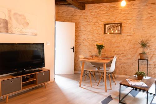 een woonkamer met een tafel en een televisie bij Immeuble 3 Apparts Centre historique St Gilles MaisoncarreeConciergerie in Saint-Gilles