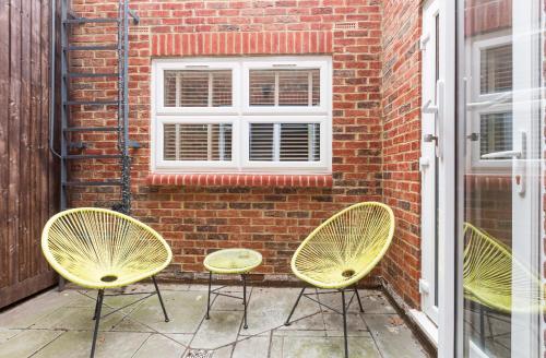 倫敦的住宿－Private room with en-suite，砖墙前坐着三把黄色椅子