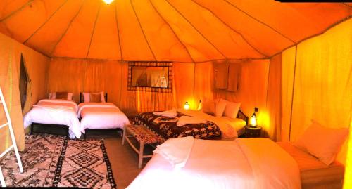 a bedroom with three beds in a tent at Horaz Merzouga Camp in Merzouga
