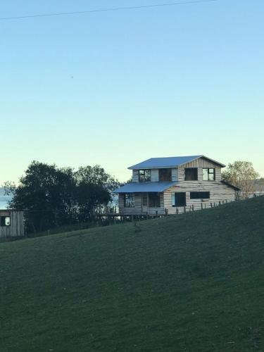 a house on top of a hill with a field at ARRIENDO DIARIO PUQUELDON-CHILOE, SECTOR PLAYA LINCAY in Puqueldón