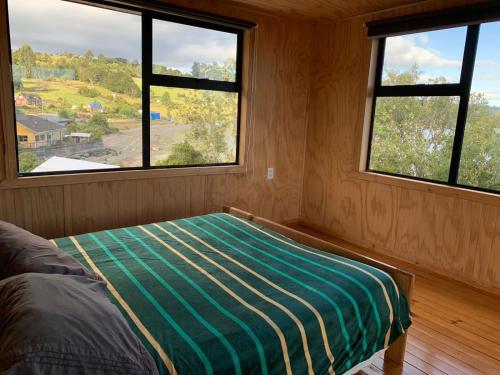 1 dormitorio con 2 ventanas y 1 cama. en ARRIENDO DIARIO PUQUELDON-CHILOE, SECTOR PLAYA LINCAY, en Puqueldón