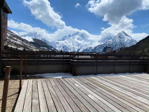 a view of snow covered mountains from a wooden deck at Résidence Champame - Studio pour 4 Personnes 251 in Vénosc