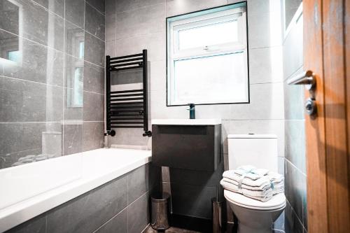 een badkamer met een toilet, een bad en een raam bij Primrose House - 3 Bedroom Home in Manchester in Manchester