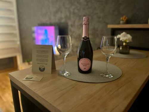 uma garrafa de vinho e dois copos de vinho numa mesa em Lux Apartman Aleksandar em Zlatibor