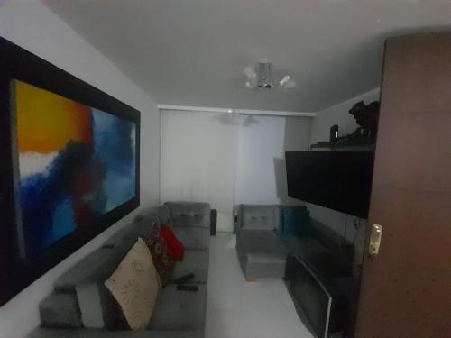 sala de estar con sofá y TV de pantalla plana en APARTAHOTEL PALMETTO, en Neiva