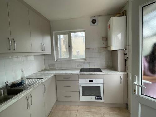 a kitchen with white cabinets and a sink and a refrigerator at Dudley court, Lower Road in Harrow on the Hill