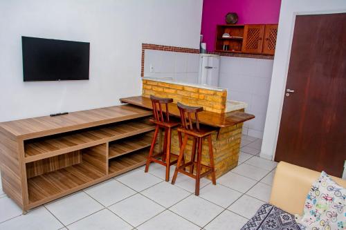 a kitchen with a bar with two stools and a tv at Pousada Flat Castor in Natal