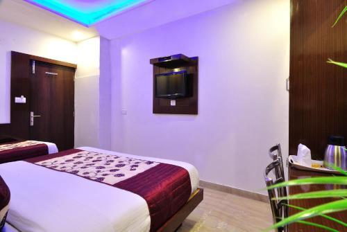 Una habitación de hotel con una cama y un televisor en la pared. en Hotel Nirmal Mahal - Paharganj - New Delhi, en Nueva Delhi