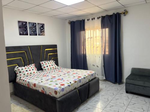 a bedroom with a bed and a couch and a chair at DAC IMMOBILIER in Yaoundé