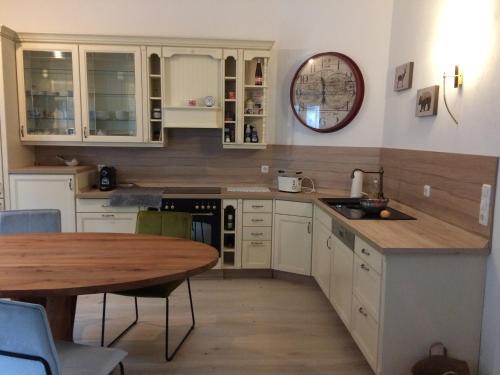 a kitchen with white cabinets and a wooden table at SistiHome in Kleinfeistritz