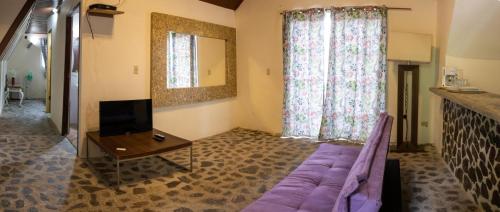 un salon avec un canapé violet et une télévision dans l'établissement Refugio Cariguana, à El Valle de Antón