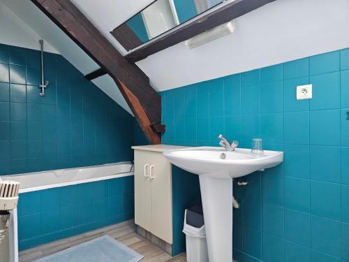 La salle de bains est pourvue d'un lavabo et de carrelage bleu. dans l'établissement Appartement du haut 1, à Cordemais