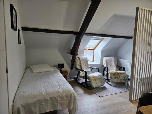 a bedroom with a bed and two chairs in a attic at Appartement du haut 1 in Cordemais