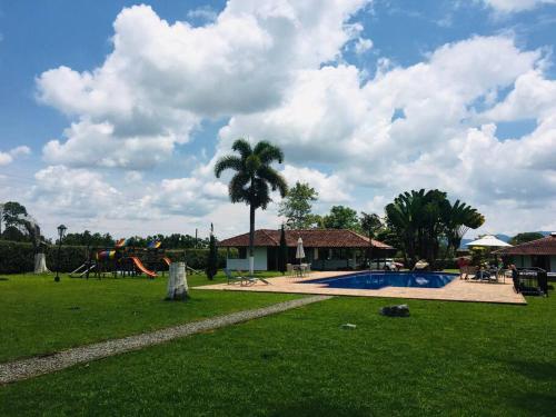 une piscine avec un palmier et une aire de jeux dans l'établissement Villa campestre en el Quindío con piscina, bbq, zonas verdes cerca al Parque del Café, à Montenegro