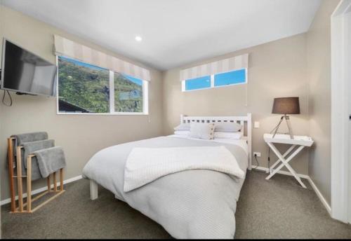 a bedroom with a white bed and a television at Twin Rivers Spa Retreat in Queenstown