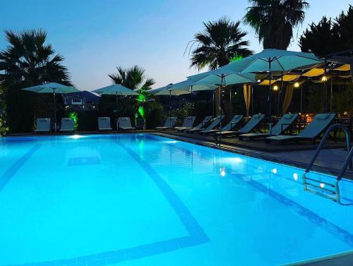 a swimming pool with chairs and umbrellas at night at MAVİ ROTA BUTİK OTEL in Datca