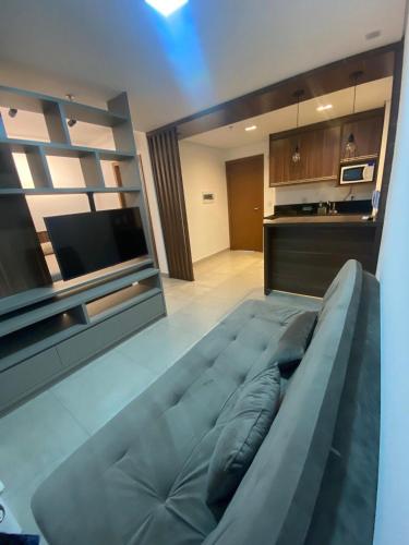a living room with a large couch and a tv at Monte Carmel in Ribeirão Preto