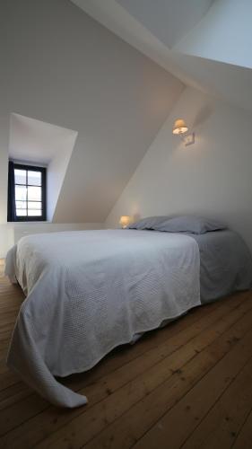 a bedroom with a bed with white sheets and a window at Villa Joséphine 4-11 personnes in Asnelles