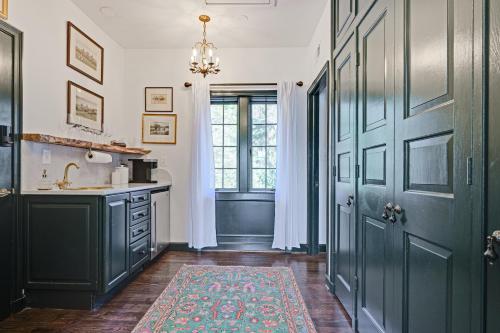 a kitchen with green cabinets and a sink and a door at Historic Maryland Gatehouse Pool Access and Balcony in Cockeysville