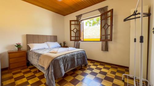 a bedroom with a bed and a window at Dúplex Jaguaribe in Campos do Jordão