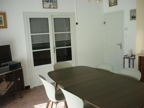 une salle à manger avec une table noire et des chaises blanches dans l'établissement maison 20mn de la mer, à Aigrefeuille-dʼAunis