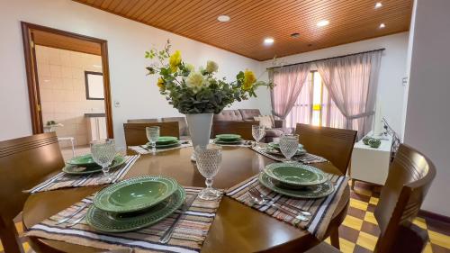 a dining room table with green plates and a vase of flowers at Dúplex Jaguaribe in Campos do Jordão