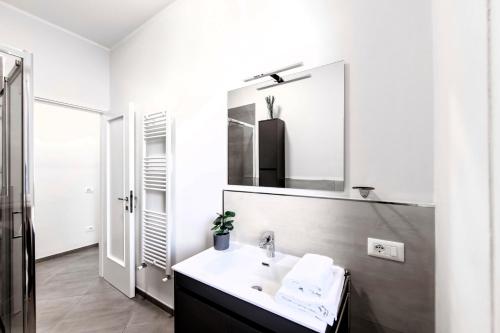 bagno bianco con lavandino e specchio di Hostly-Family Home Ardenza-Near the seaside a Livorno