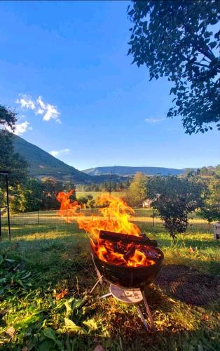 a barbecue grill with flames in a field at Sole Tiny House in Šipovo