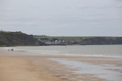 a beach with a group of people standing in the water at Villa Joséphine 4-11 personnes in Asnelles