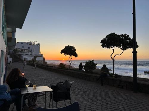a group of people sitting at a table watching the sunset at Hola ola Bajamar in Bajamar