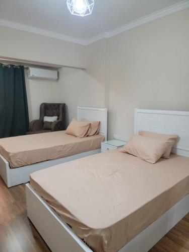 a bedroom with two beds and a chair in it at Dokii in Cairo