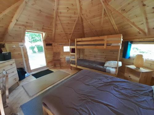 une chambre dans une cabane en rondins avec un lit dans l'établissement kota camping lac de Bairon, à Le Chesne