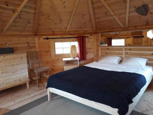 une chambre avec un lit dans une cabane en bois dans l'établissement kota camping lac de Bairon, à Le Chesne
