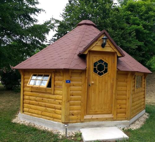 une grande cabane en bois avec un toit rouge dans l'établissement kota camping lac de Bairon, à Le Chesne