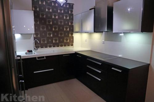 a kitchen with black cabinets and white counter tops at Cosy Beach House in Agios Vasilios, Patras in Áyios Vasílios