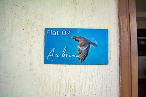 a sign on a wall with a bird in flight at Pousada Flat Castor in Natal