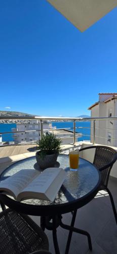 a table with a book and a drink on a balcony at 3S Apartments -Sea-Sun-Sky- in Sarandë