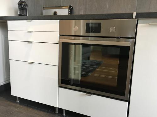 Il comprend une cuisine équipée d'une cuisinière et de placards blancs. dans l'établissement Grand Studio design avec parking, à Neuilly-sur-Seine