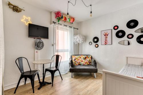 a living room with a table and chairs and a tv at Studio Pop plein Centre-Port - ménage, linge inclus in Cap d'Agde
