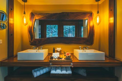 uma casa de banho com 2 lavatórios e um espelho em Amor Arenal Adults Friendly em La Fortuna
