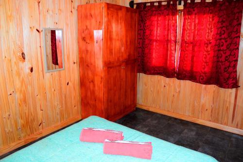 a small room with a bed with red curtains at Casitas Nuova Villa in Puerto Iguazú