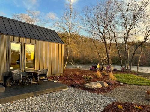 Asheville River Cabins في Arden: منزل صغير مع طاولة وكراسي في الأمام