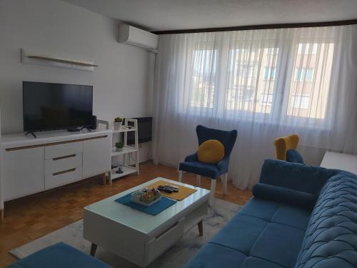 salon z niebieską kanapą i telewizorem w obiekcie Apartman Zenica w mieście Zenica