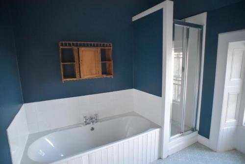 uma banheira na casa de banho com uma parede azul em Traditional Family Stone Farmhouse, sleeps 12, St Andrews em St. Andrews