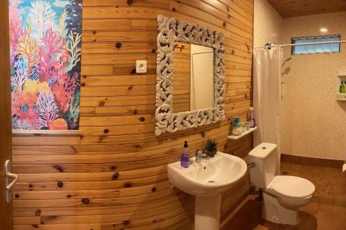 a bathroom with a wooden wall with a toilet and a sink at Rangiroa Sunny House in Avatoru
