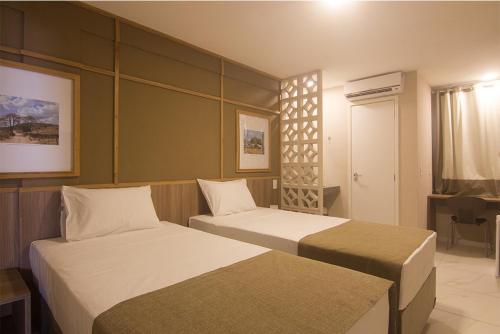 a hotel room with two beds and a television at Hotel Privillege in SantʼAnna do Ipanema